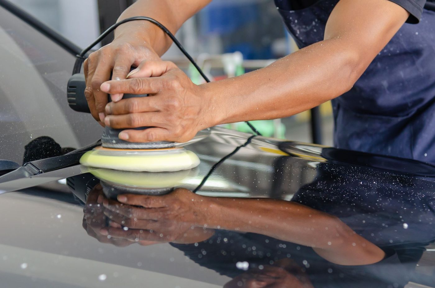 A machine polisher being worked across a car's paintwork