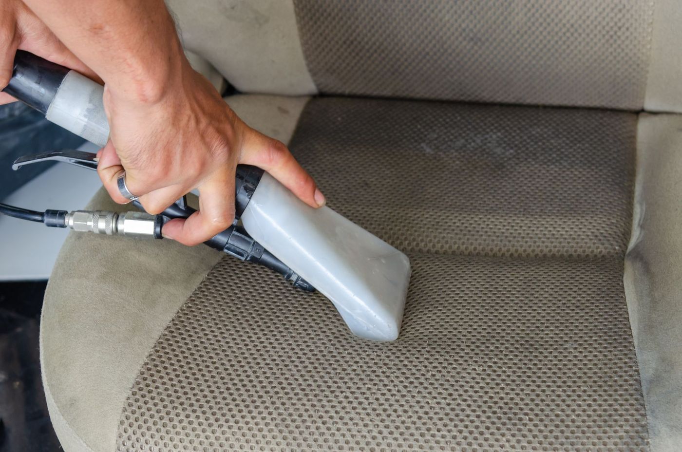 A hot-water extractor cleaning a fabric car seat